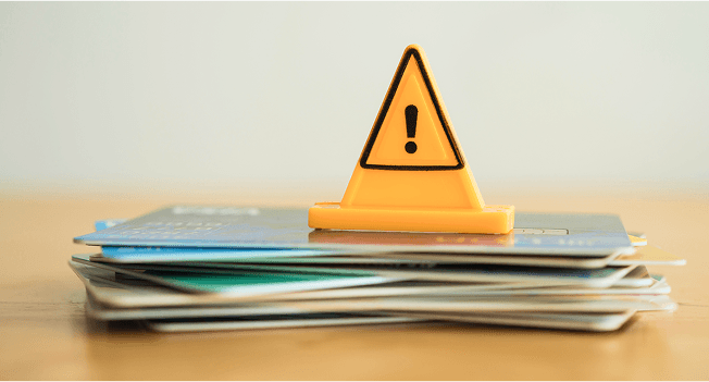 積み重なったクレジットカードとビックリマークの置き物